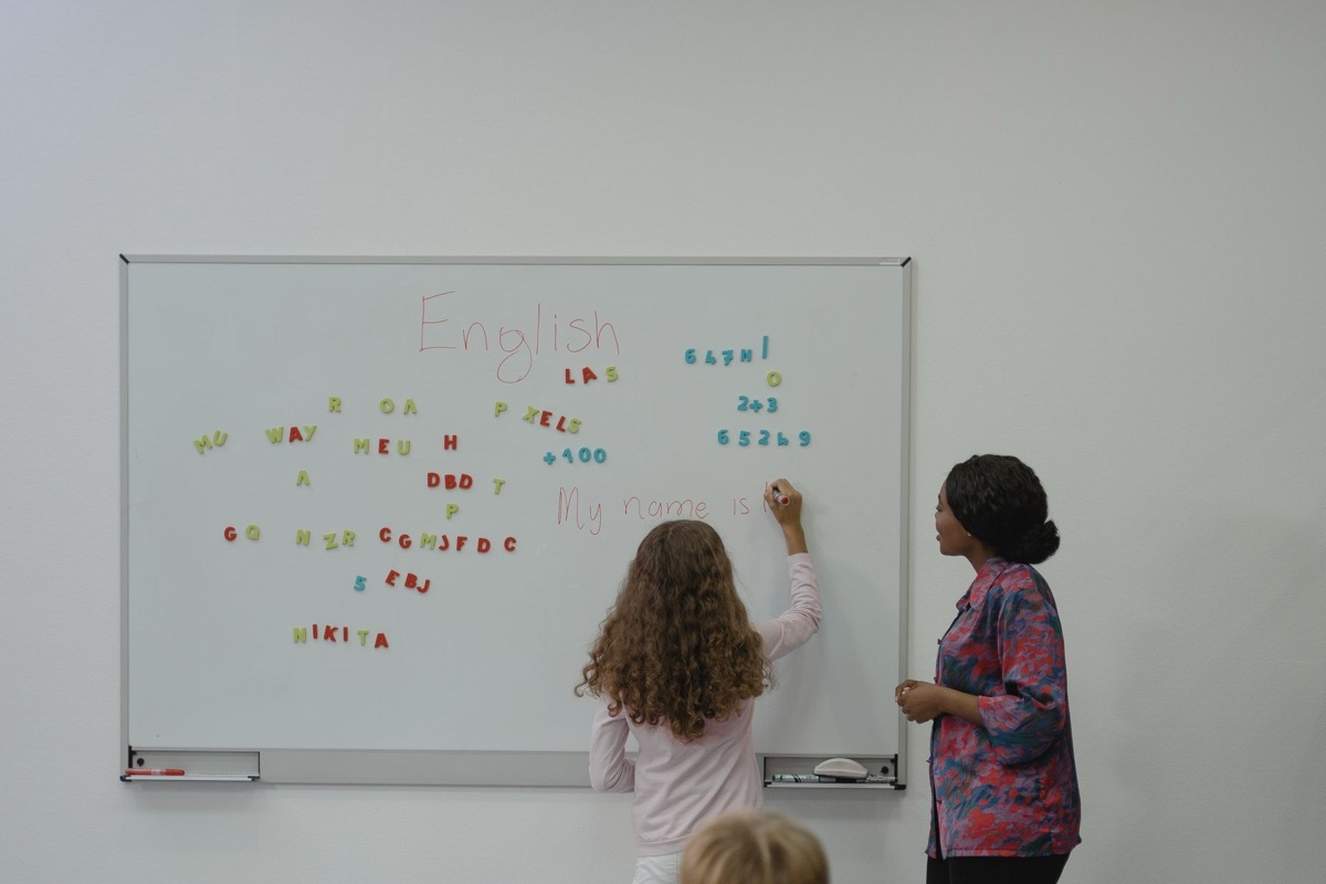Bambina scrive English alla lavagna durante la lezione
