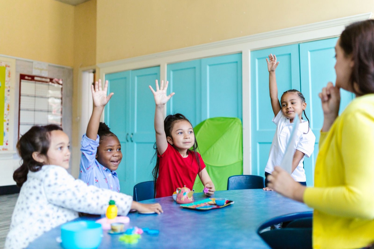 Bambini che alzano la mano durante la lezione in aula